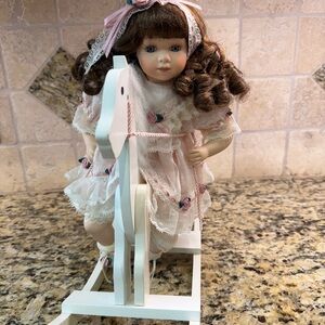 12” Porcelain Doll with curly brown hair and blue eyes.